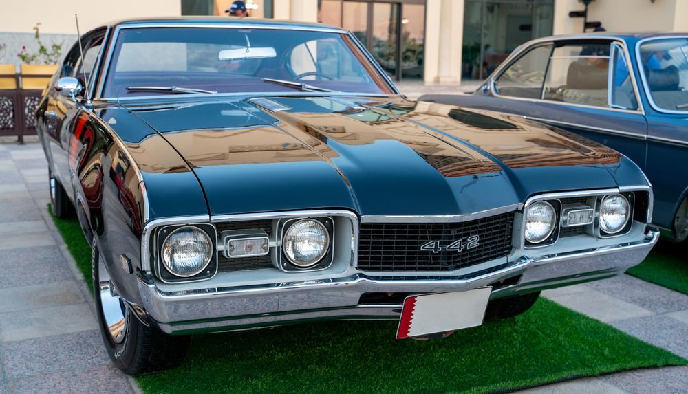 Black classic convertible car with chrome grille parked on artificial grass at a car show