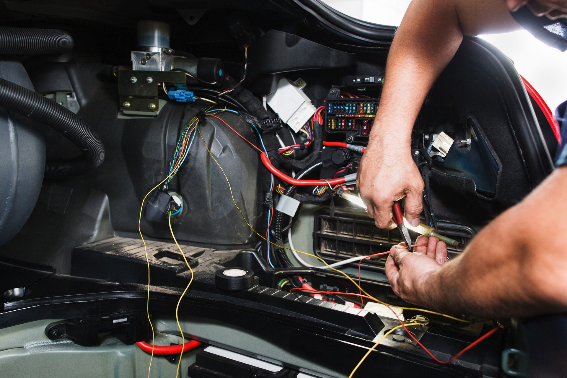 Hands wiring an electrical panel inside a vehicle dashboard