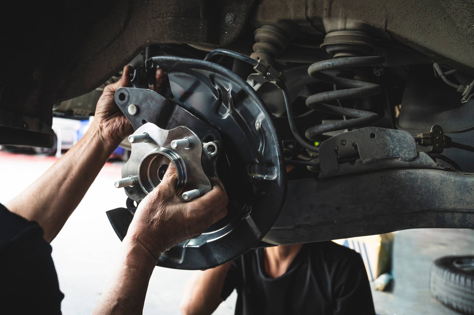 Mechanic installing a car brake rotor and caliper inside a wheel well