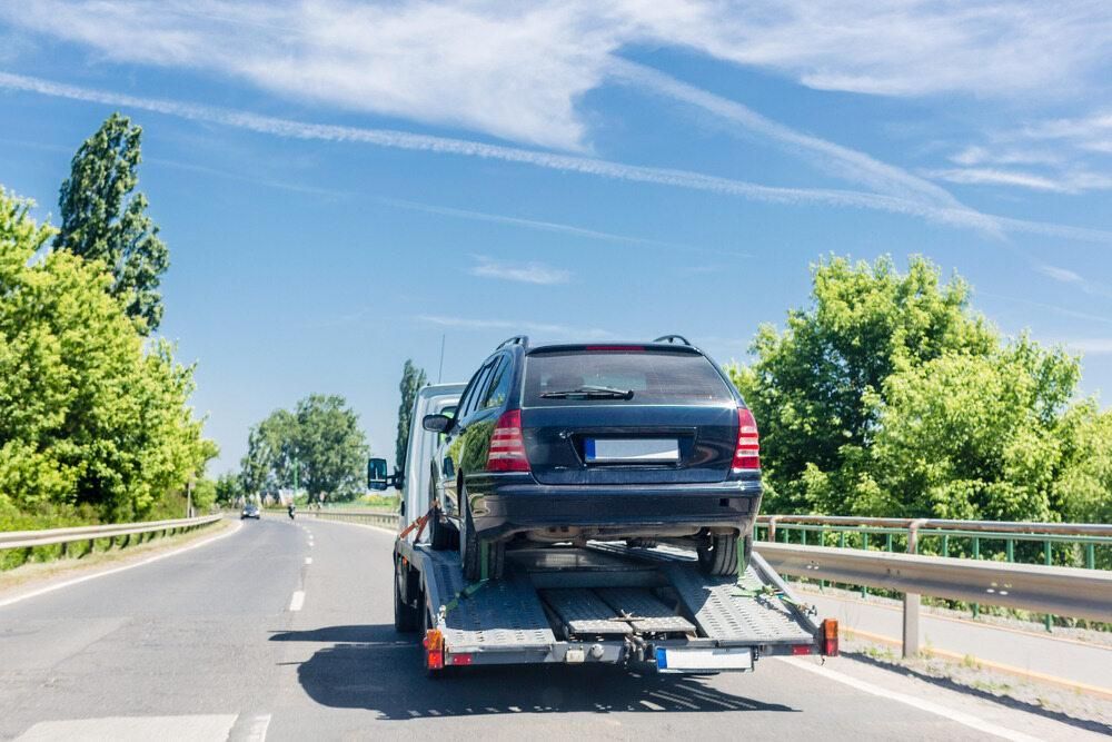 A Car is Being Towed Down a Highway by a Tow Truck — Bulahdelah Towing In Stroud, NSW
