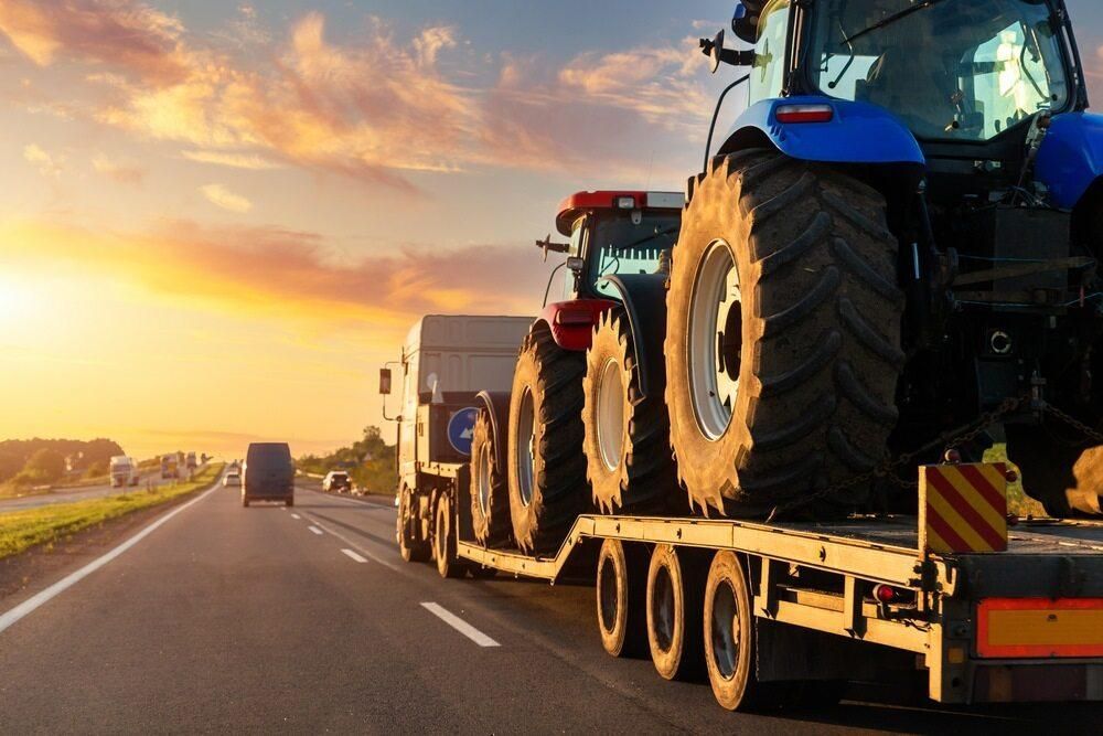 A Tractor is Being Towed by a Semi Truck on a Highway — Bulahdelah Towing In Karuah, NSW