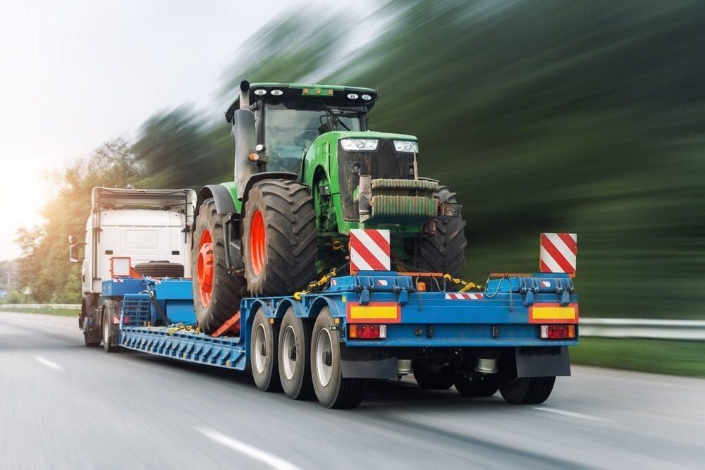 A Tractor is Being Transported on a Trailer on a Highway — Bulahdelah Towing In Bulahdelah, NSW