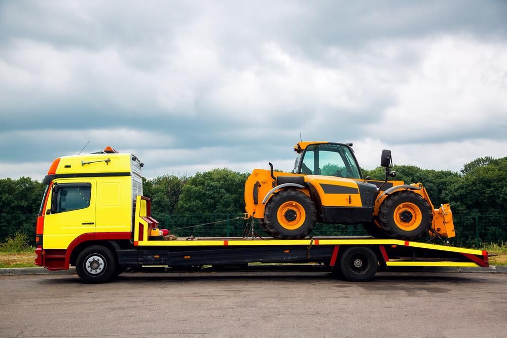 A Yellow Tow Truck is Carrying a Yellow Tractor — Bulahdelah Towing In Karuah, NSW