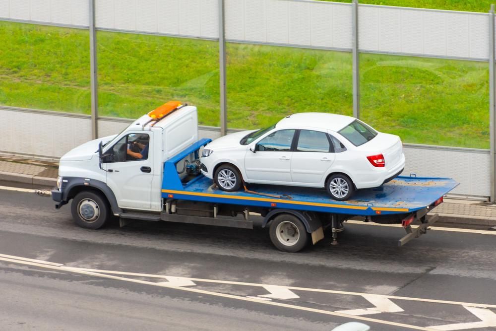 A White Car is Being Towed by a Tow Truck — Bulahdelah Towing In Karuah, NSW