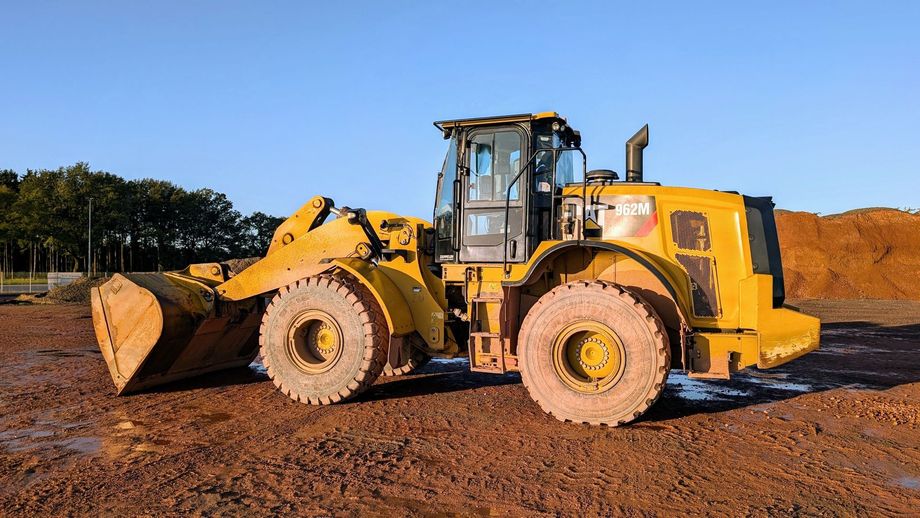 Yellow front loader on a dirt lot under a clear blue sky