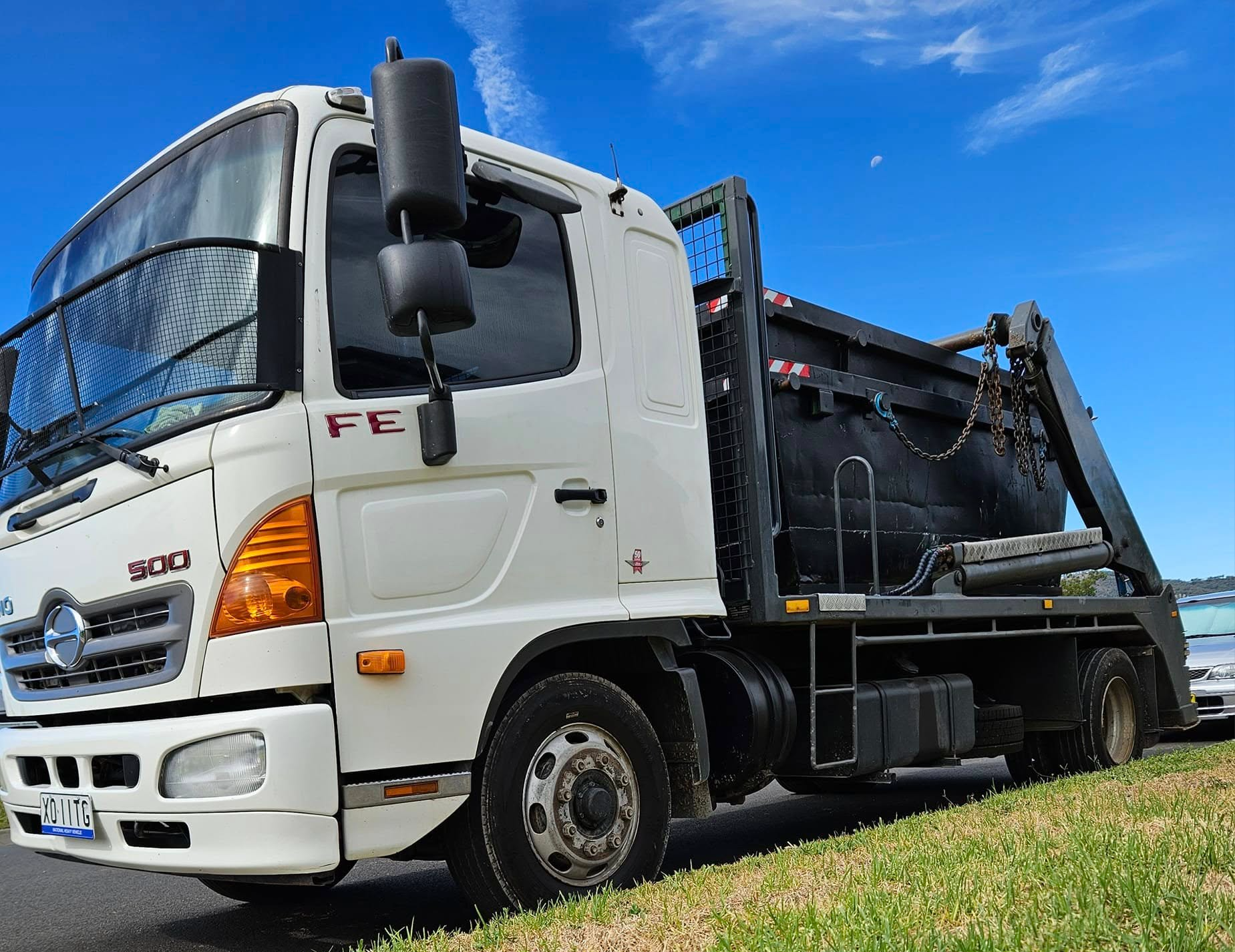 White Hino Truck With a Black Container on a Sunny Day — Tamworth Skips and Rubbish Removal in South Tamworth, NSW