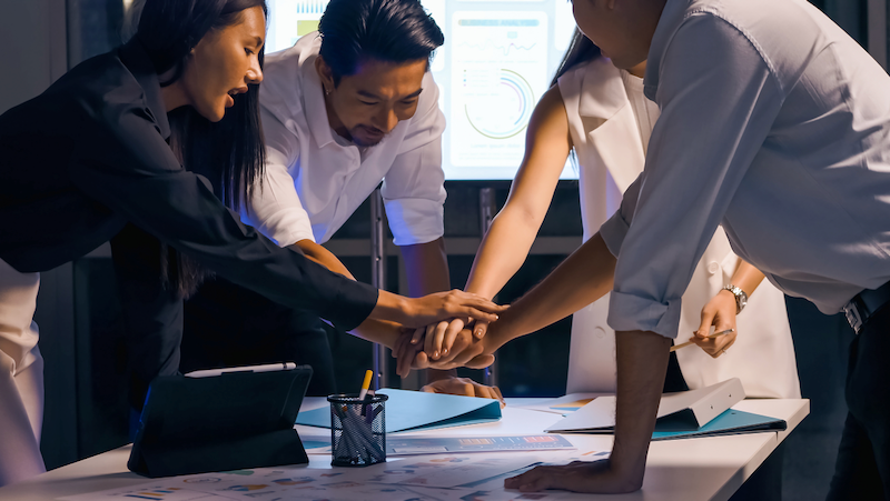A group of people are putting their hands together in an office.