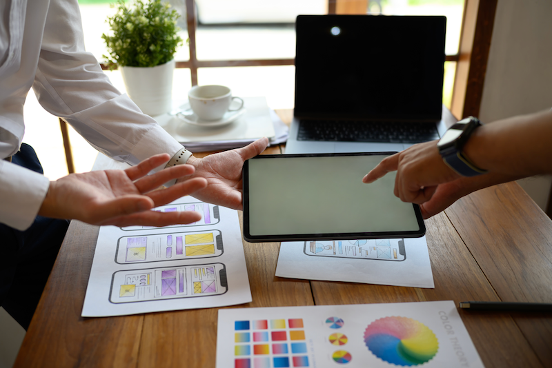 Two people are sitting at a table looking at a tablet.