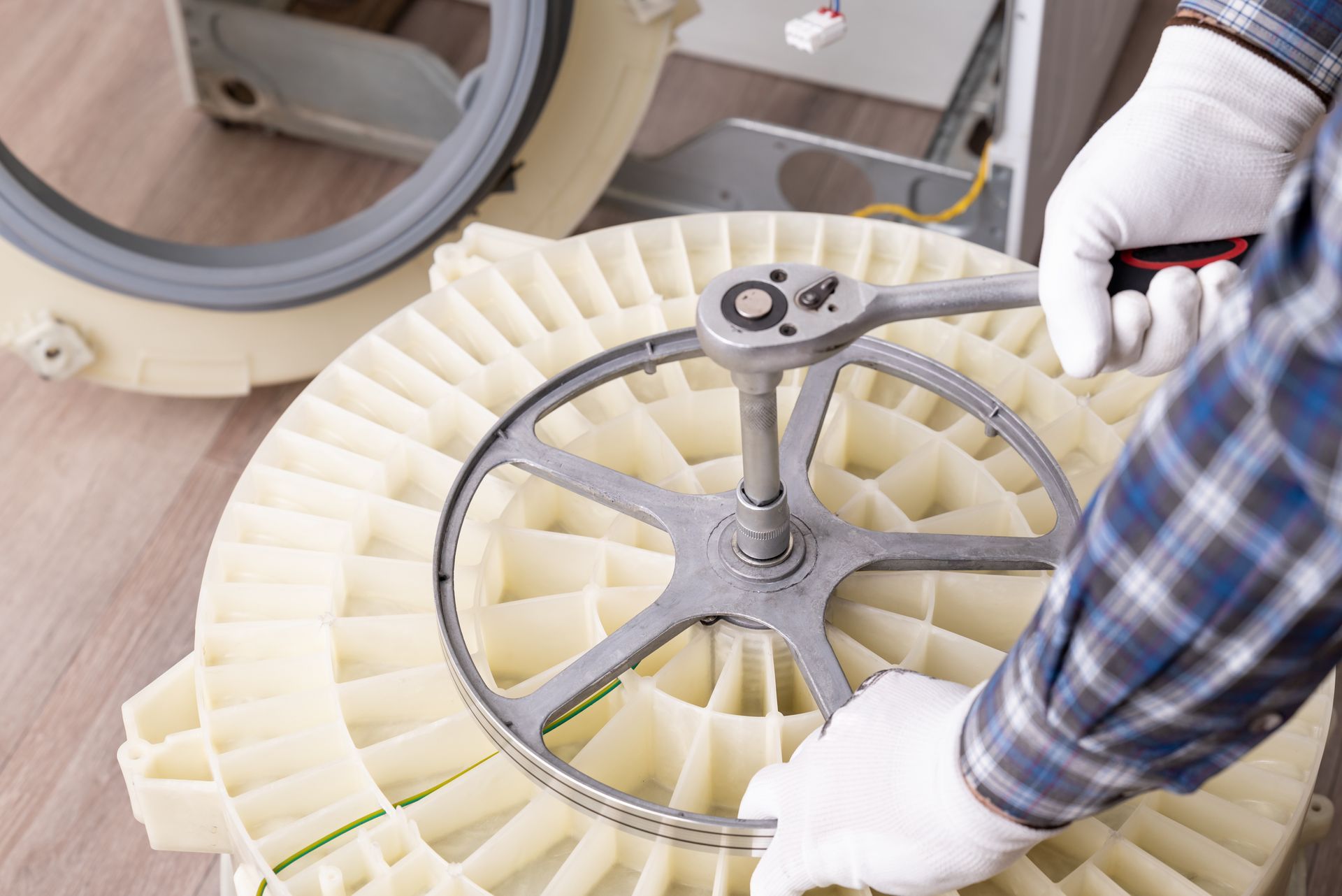 Gloved worker assembling a circular mechanical component with a wrench on a workbench