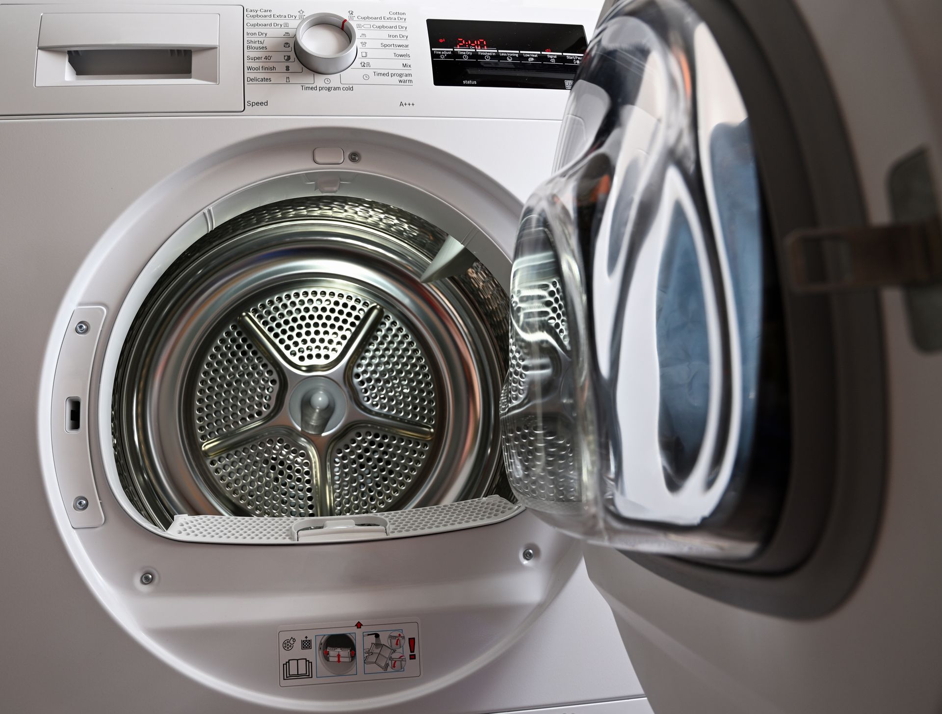 Open front-loading washing machine with the door ajar and visible metal drum inside