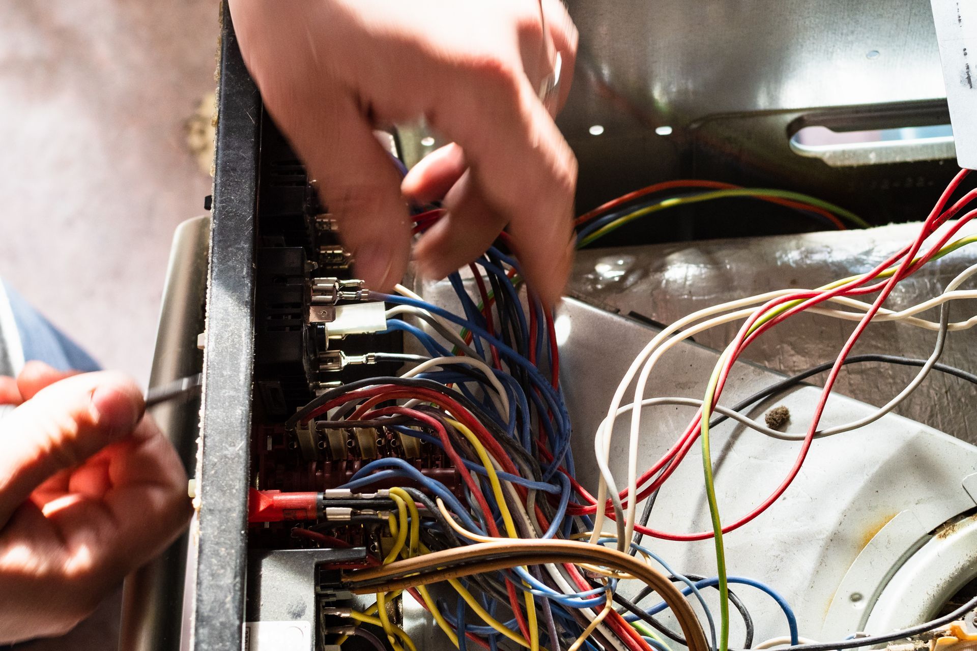 Hands working inside an open computer case with tangled multicolored wires and cables