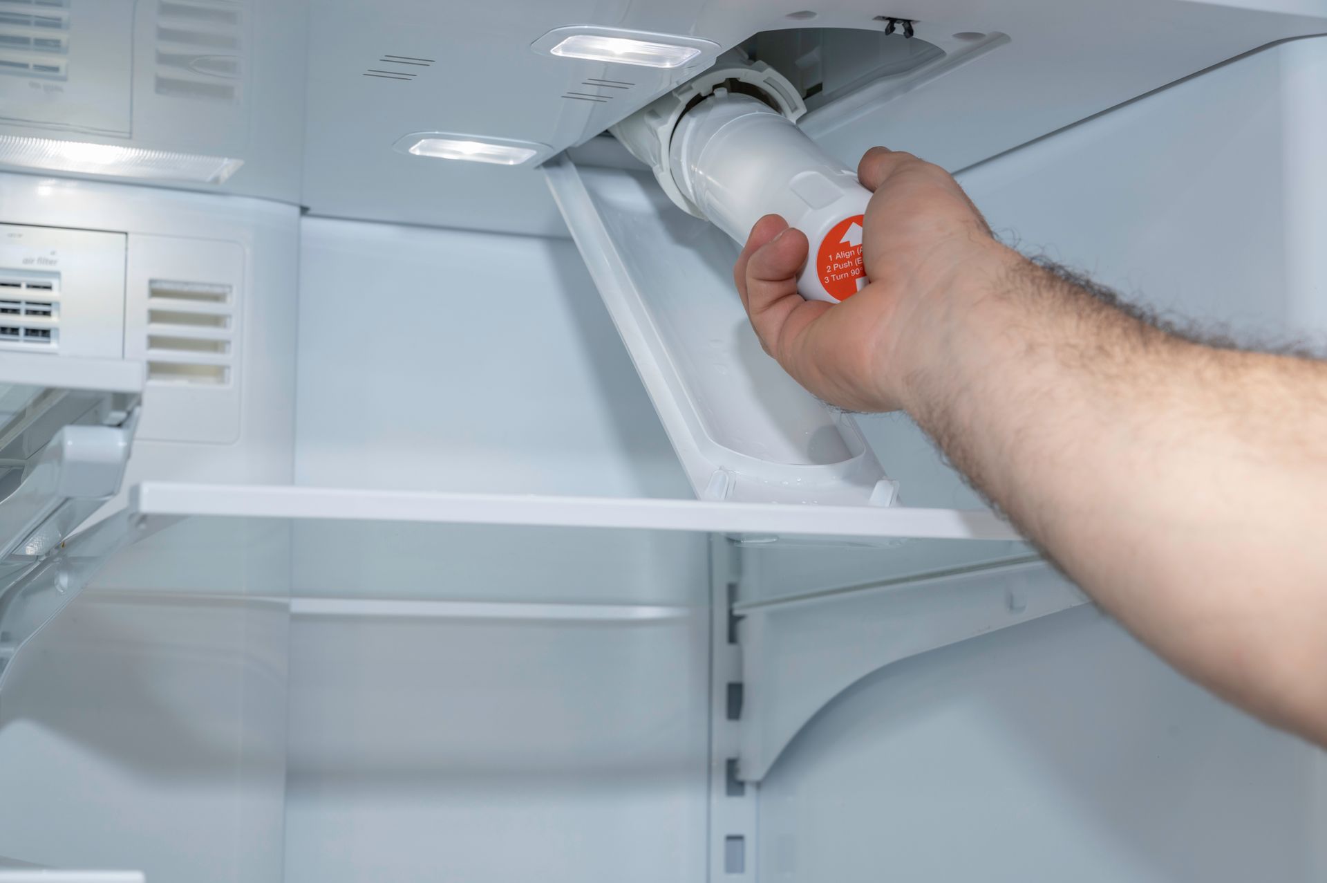 Hand opening a freezer compartment inside a white refrigerator