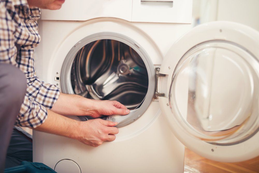 Person loading laundry into a front-loading washing machine