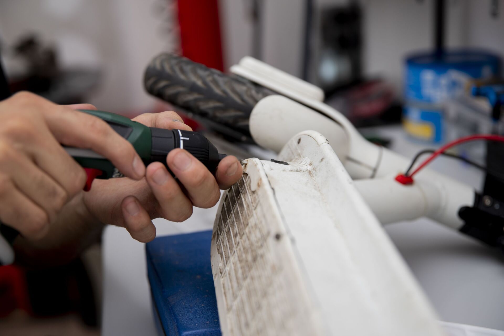 Se utiliza una pequeña herramienta rotativa para lijar o modificar el chasis de metal blanco de un patinete.