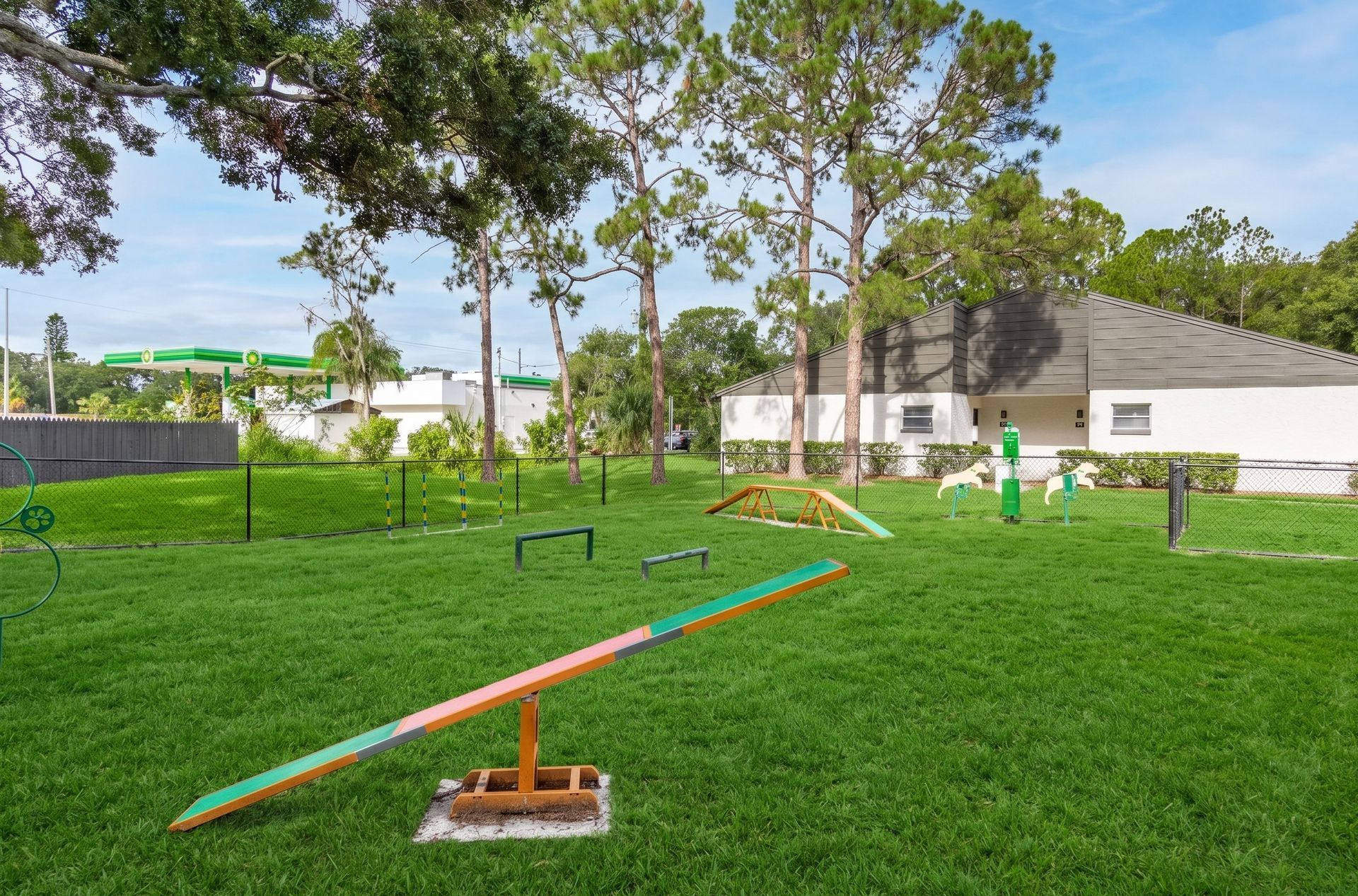 Colorful seesaw on a grassy playground with trees and a white building in the background