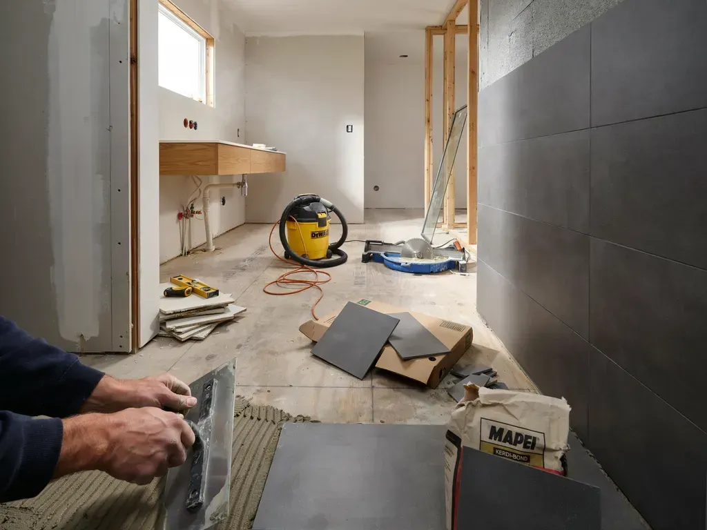 Bathroom under renovation with tools, debris, and unfinished tile work on the floor and walls