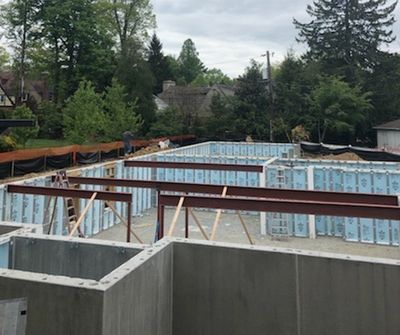 Foundation of a building under construction, with concrete walls, metal beams, and blue insulation.