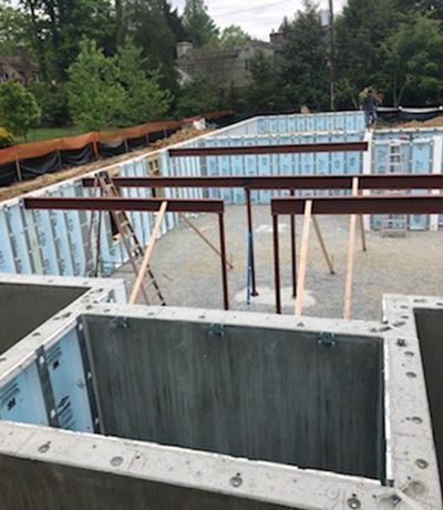 Construction site with concrete foundation walls, steel beams, and bracing.