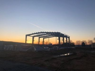 Steel frame of a building under construction against a sunset sky.
