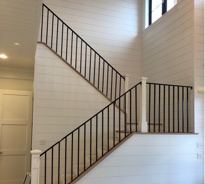 Staircase with black metal railings and white shiplap walls.