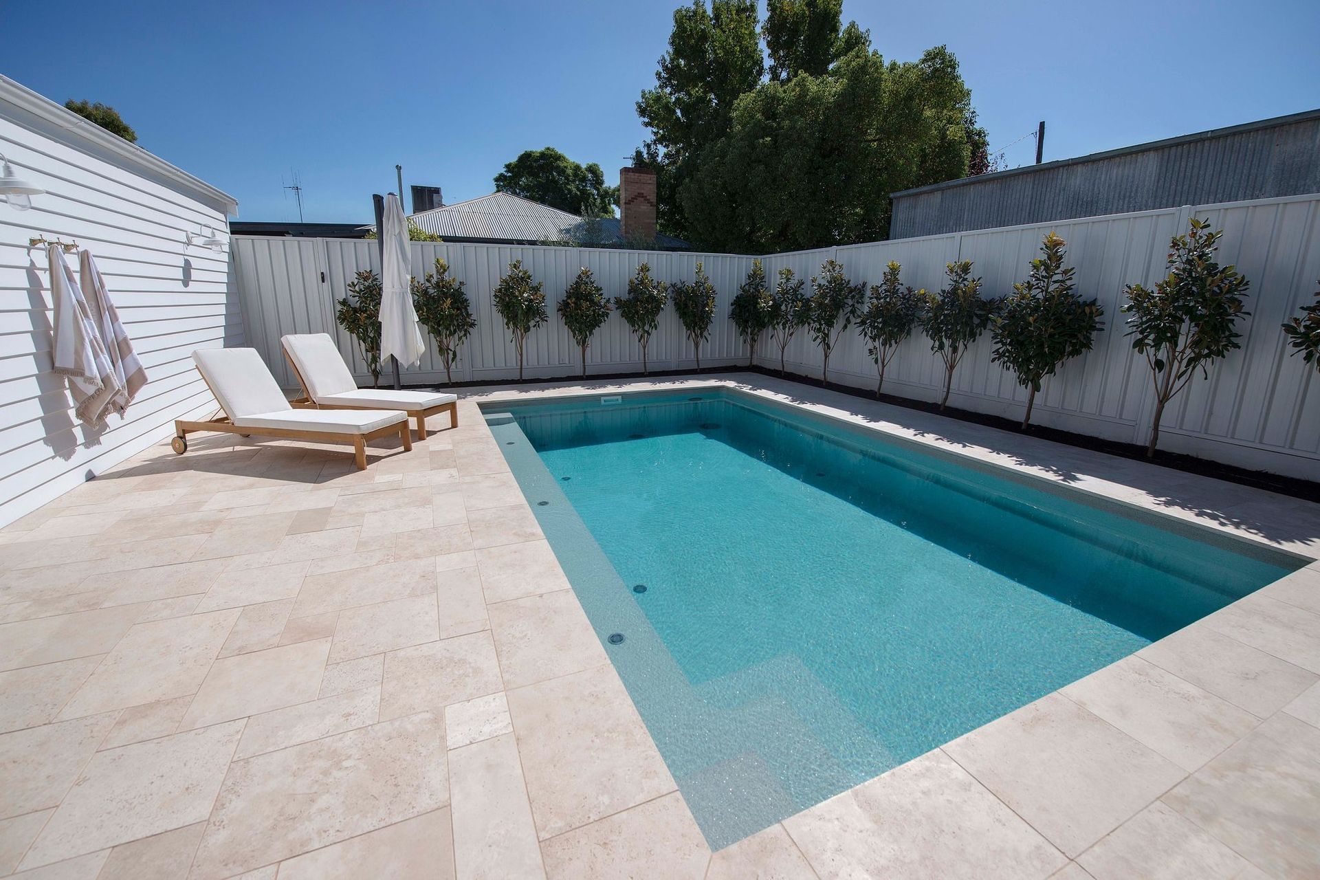 Pool Area with Lounge Chairs Surrounded by A White Fence — Swan Hill Pool & Spa Centre in Swan Hill, VIC