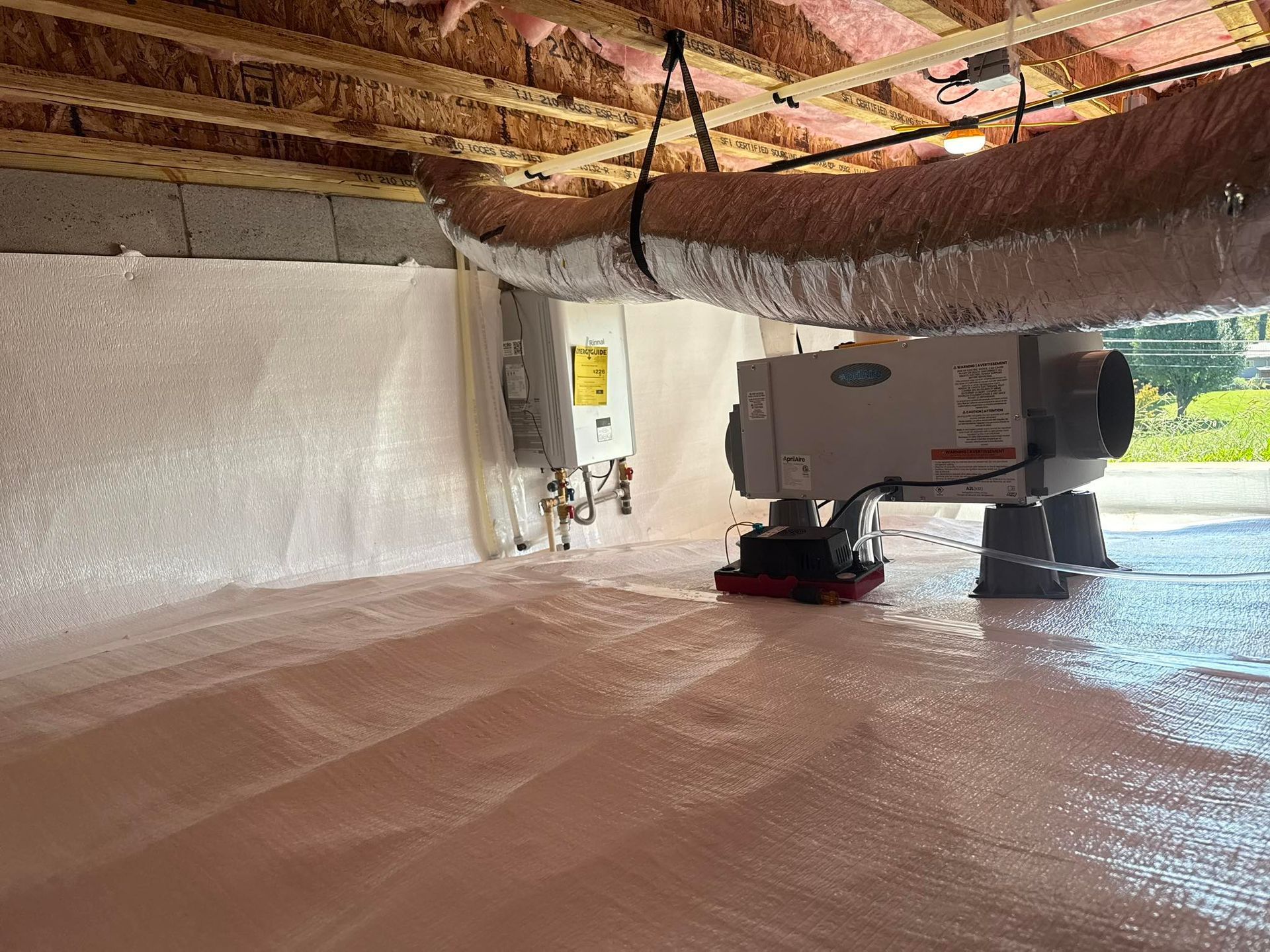 A clean crawl space with insulated walls, a vapor barrier on the floor, a dehumidifier, and exposed ceiling joists.