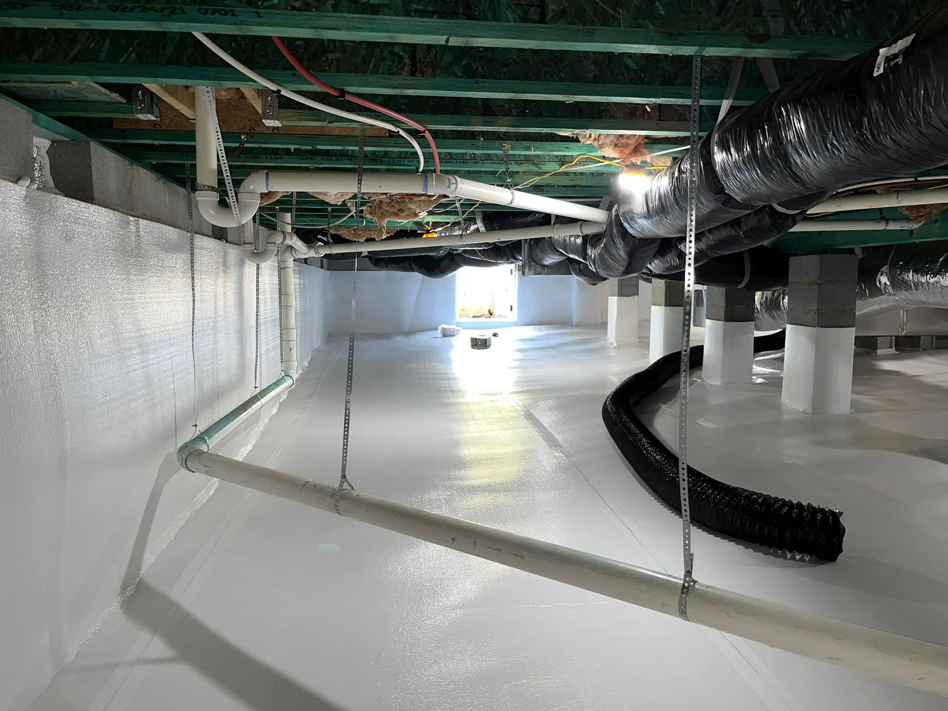 A clean, encapsulated crawlspace with white vapor barriers on the ground and walls, support pillars, and ductwork.