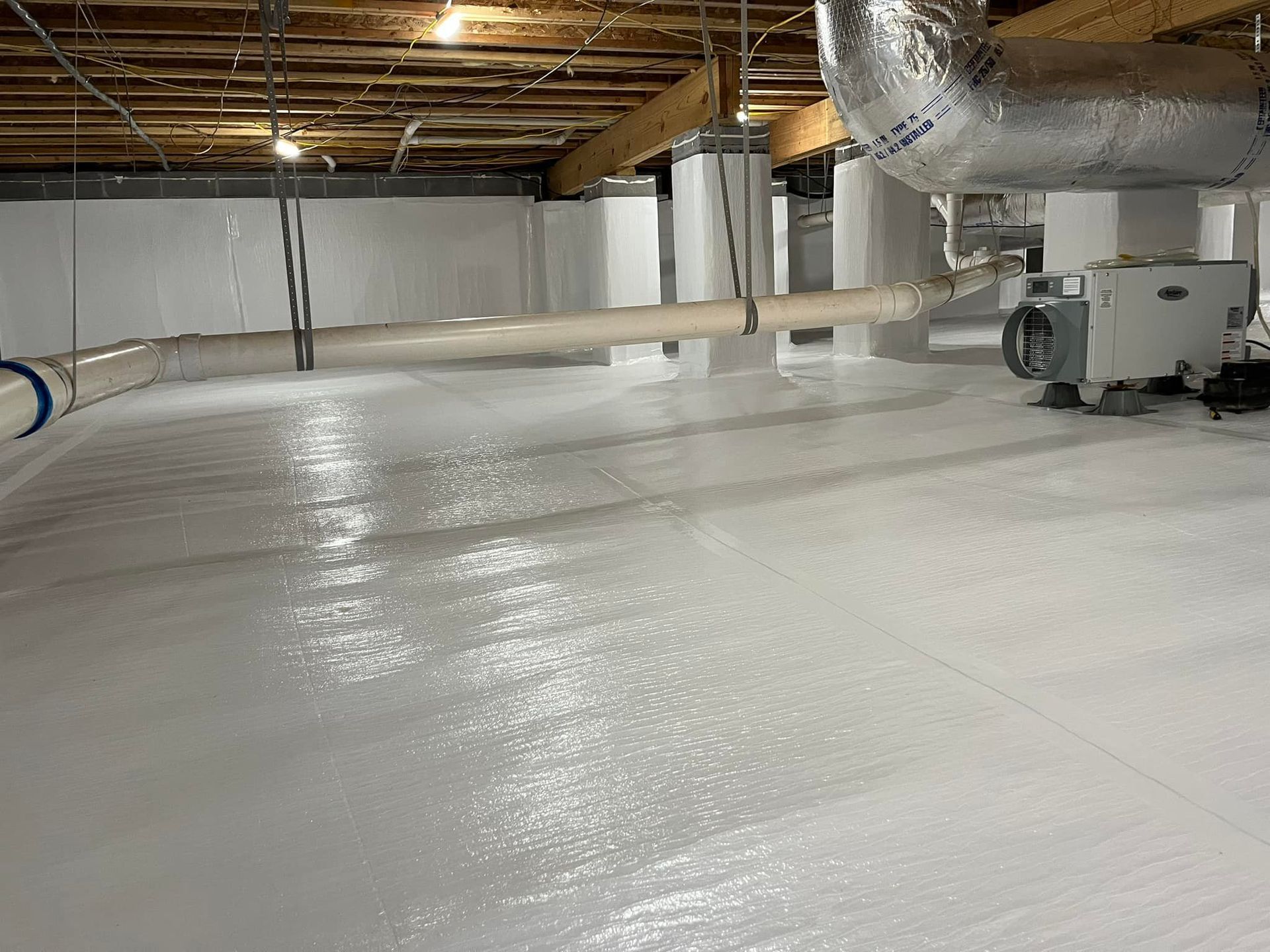 A crawl space encapsulated with bright white vapor barrier sheeting, featuring support columns and HVAC ductwork.