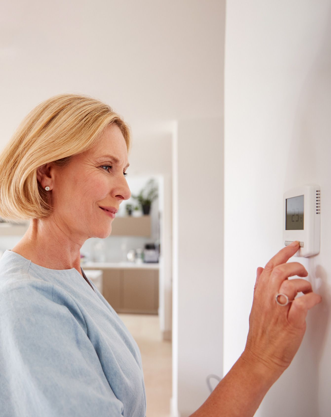 Woman Adjusting Heating Temperature — Randleman, NC — Evans Air Services Inc. Woman Adjusting Heating Temperature — Randleman, NC — Evans Air Services Inc.