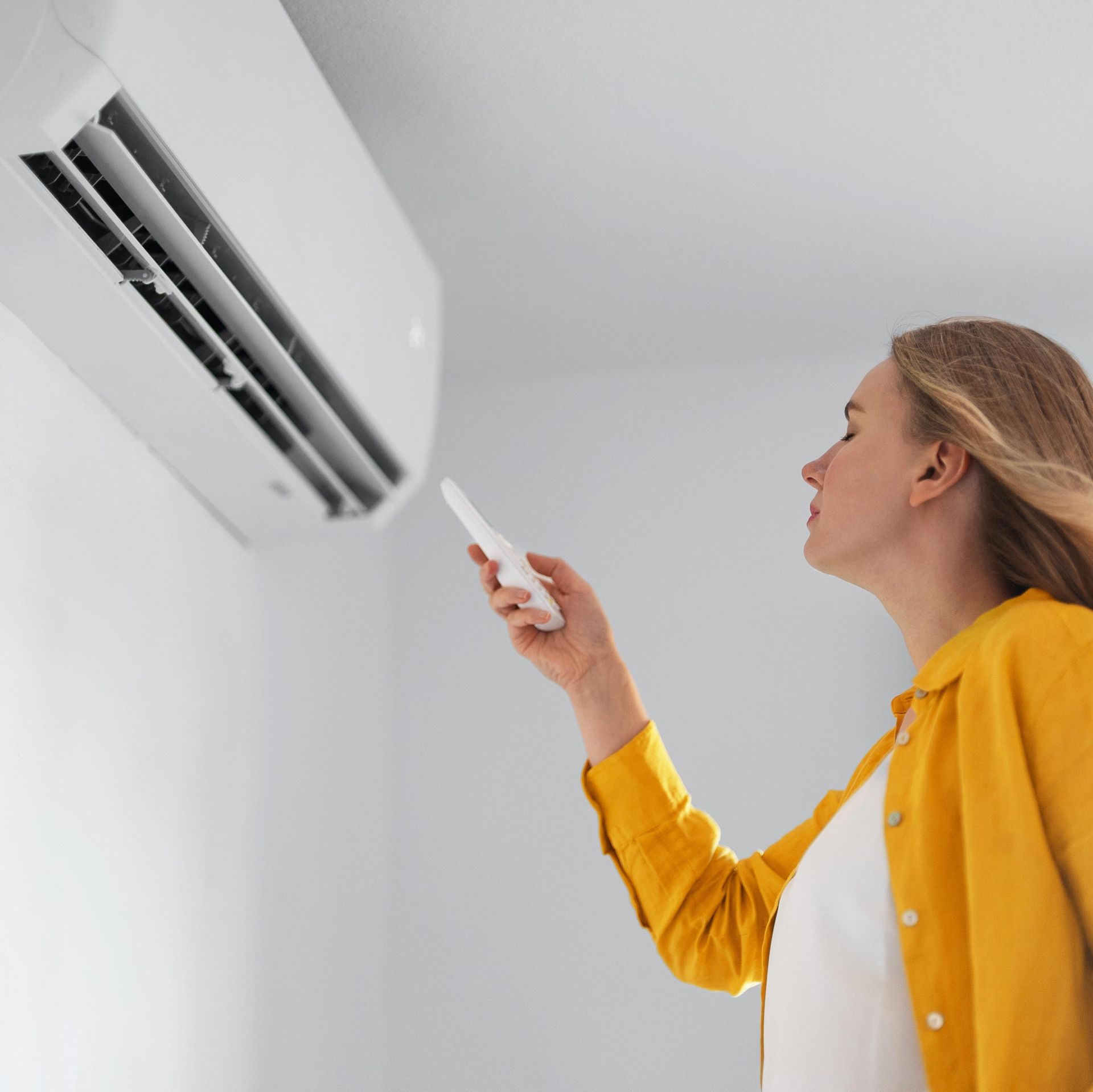 Woman Turning On Air Conditioner — Randleman, NC — Evans Air Services Inc. Woman Turning On Air Conditioner — Randleman, NC — Evans Air Services Inc.