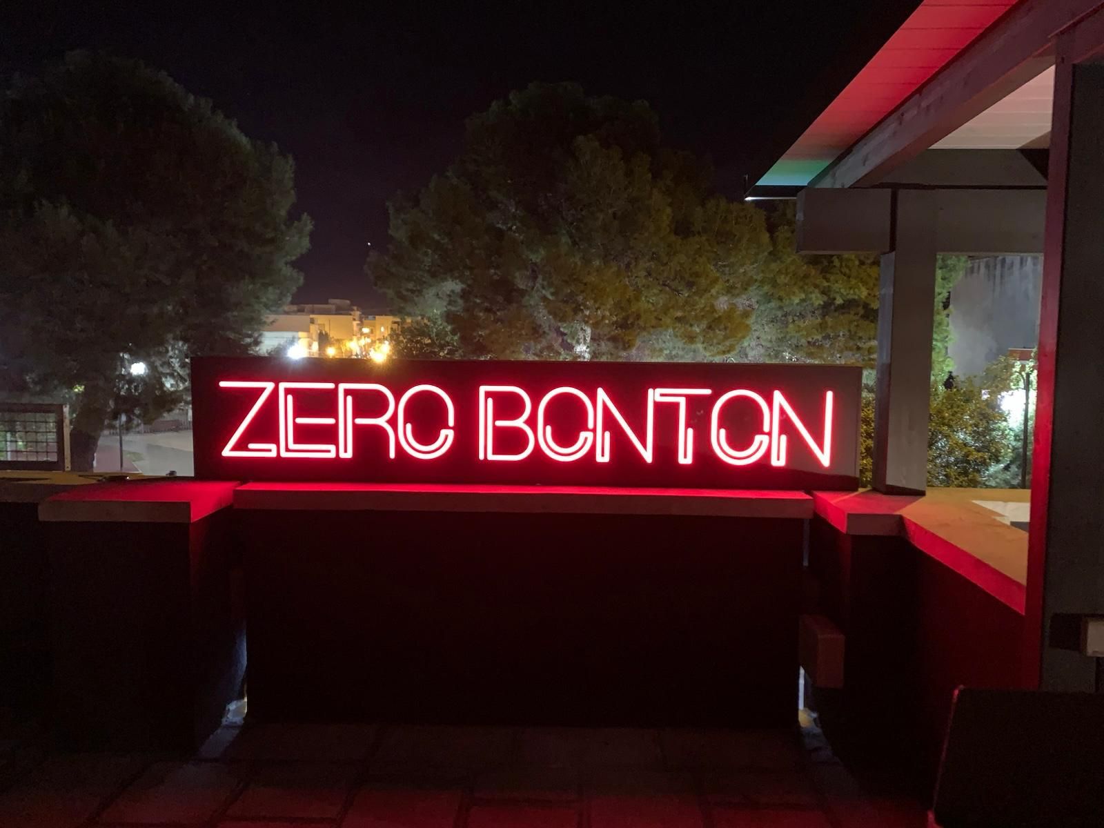 Insegna al neon con la scritta "ZERO BONTON" illuminata di rosso di notte.