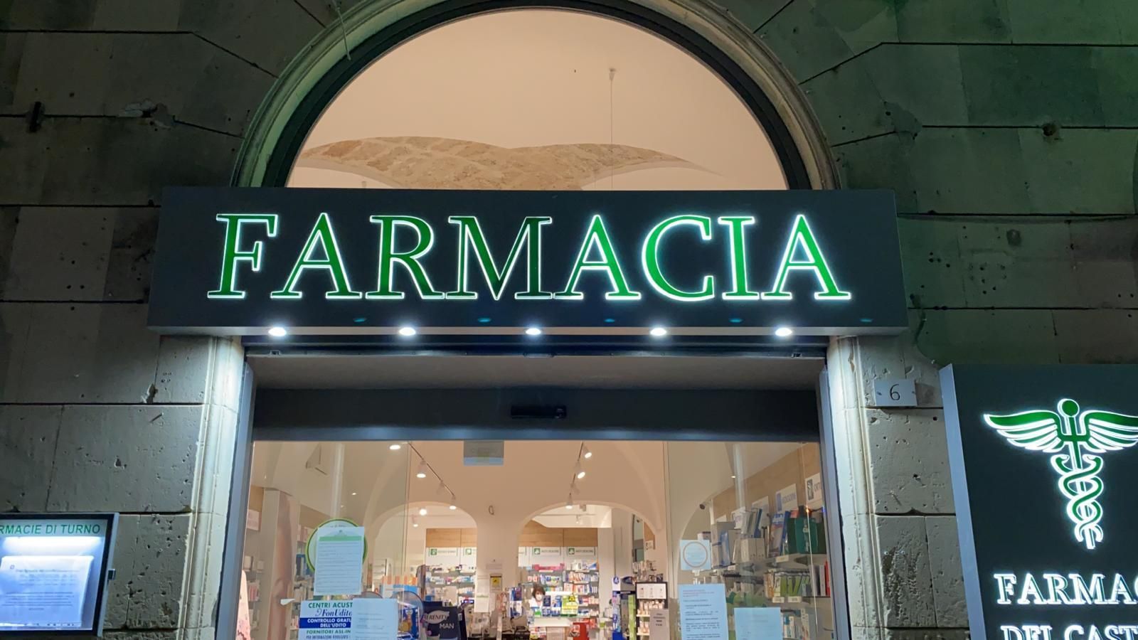 L'ingresso di una farmacia con un cartello verde illuminato con la scritta 