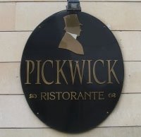 Insegna ovale nera con testo dorato e la sagoma di un uomo con un cilindro. Dice "Pickwick Ristorante".