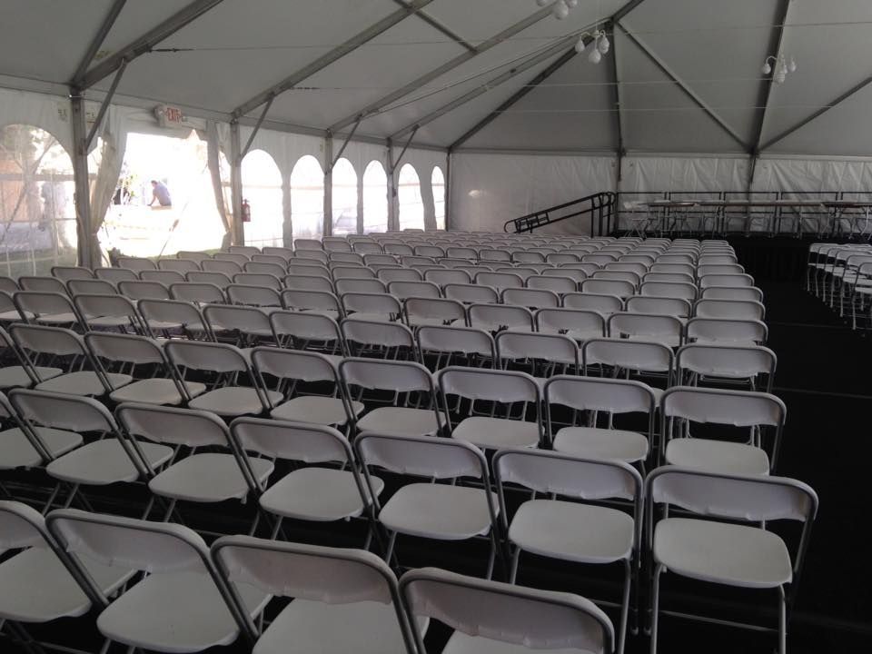Rows of White Folding Chairs Under a White Tent
