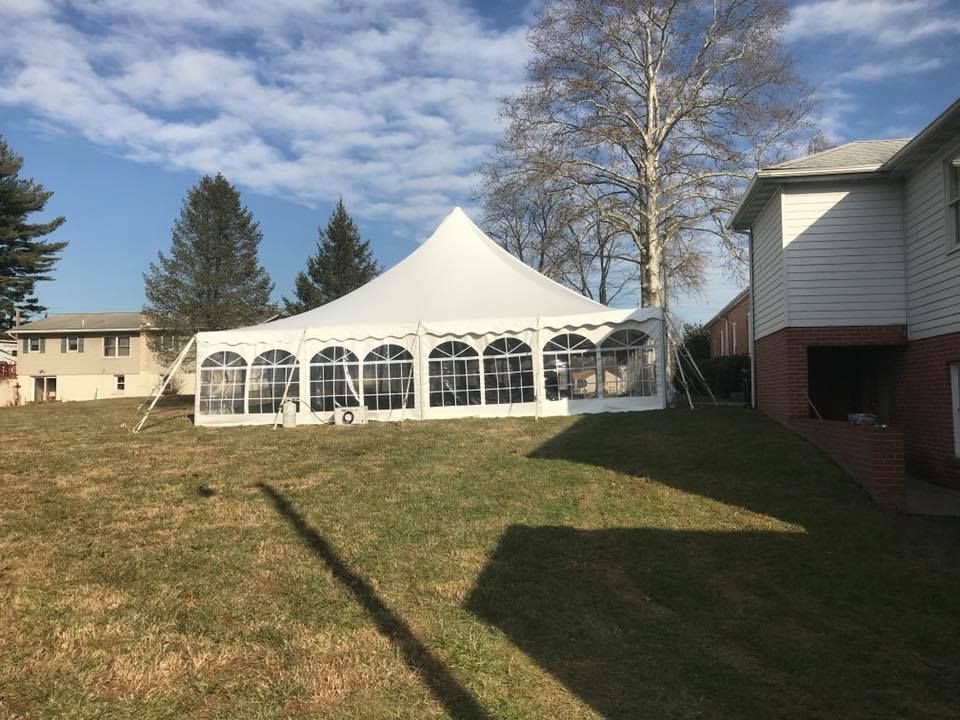 A Large White Tent is Sitting in the Grass in Front of a House