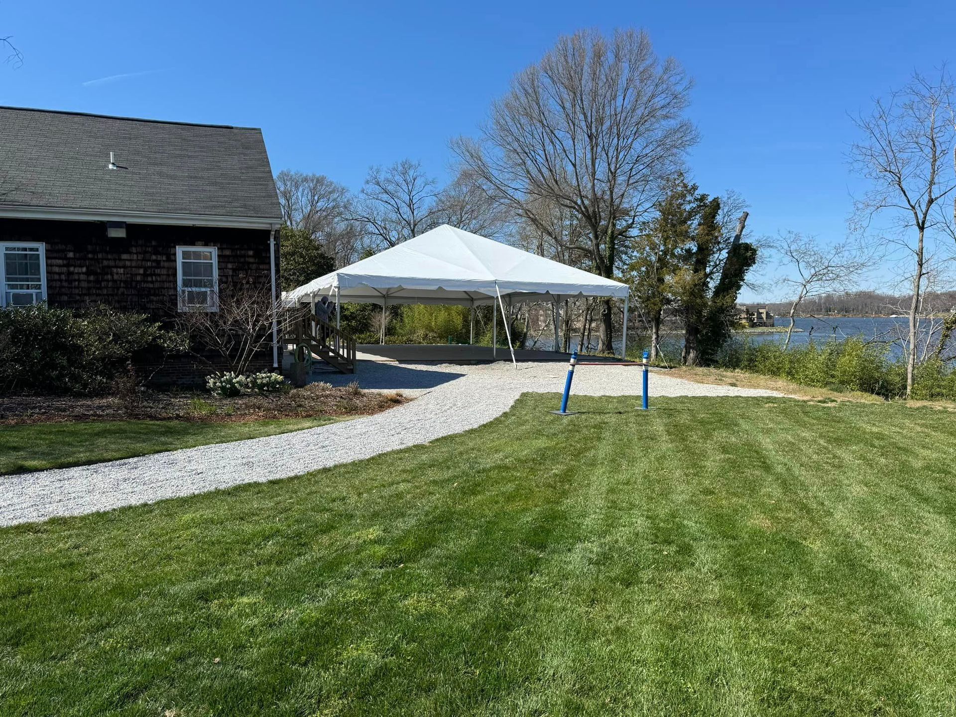 White Tent is Sitting in the Grass in Front of a House.