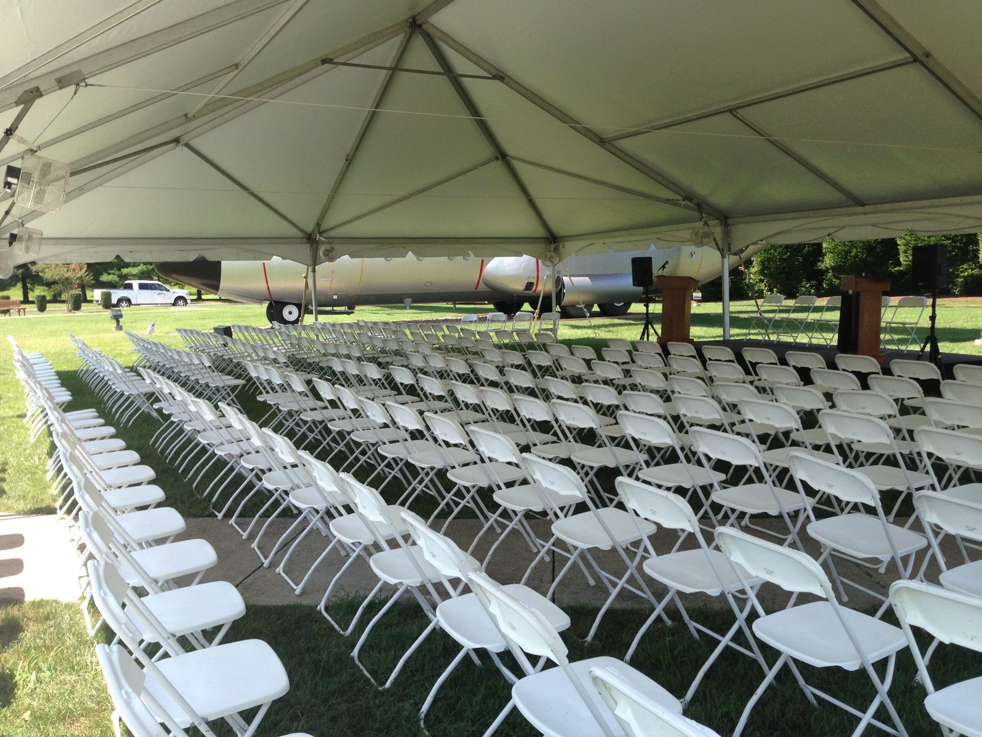 Rows of White Folding Chairs Under a Tent in a Field