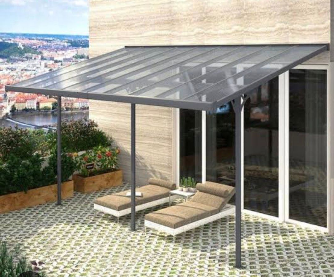 A patio with two lounge chairs under a gray-roofed awning, overlooking a cityscape.