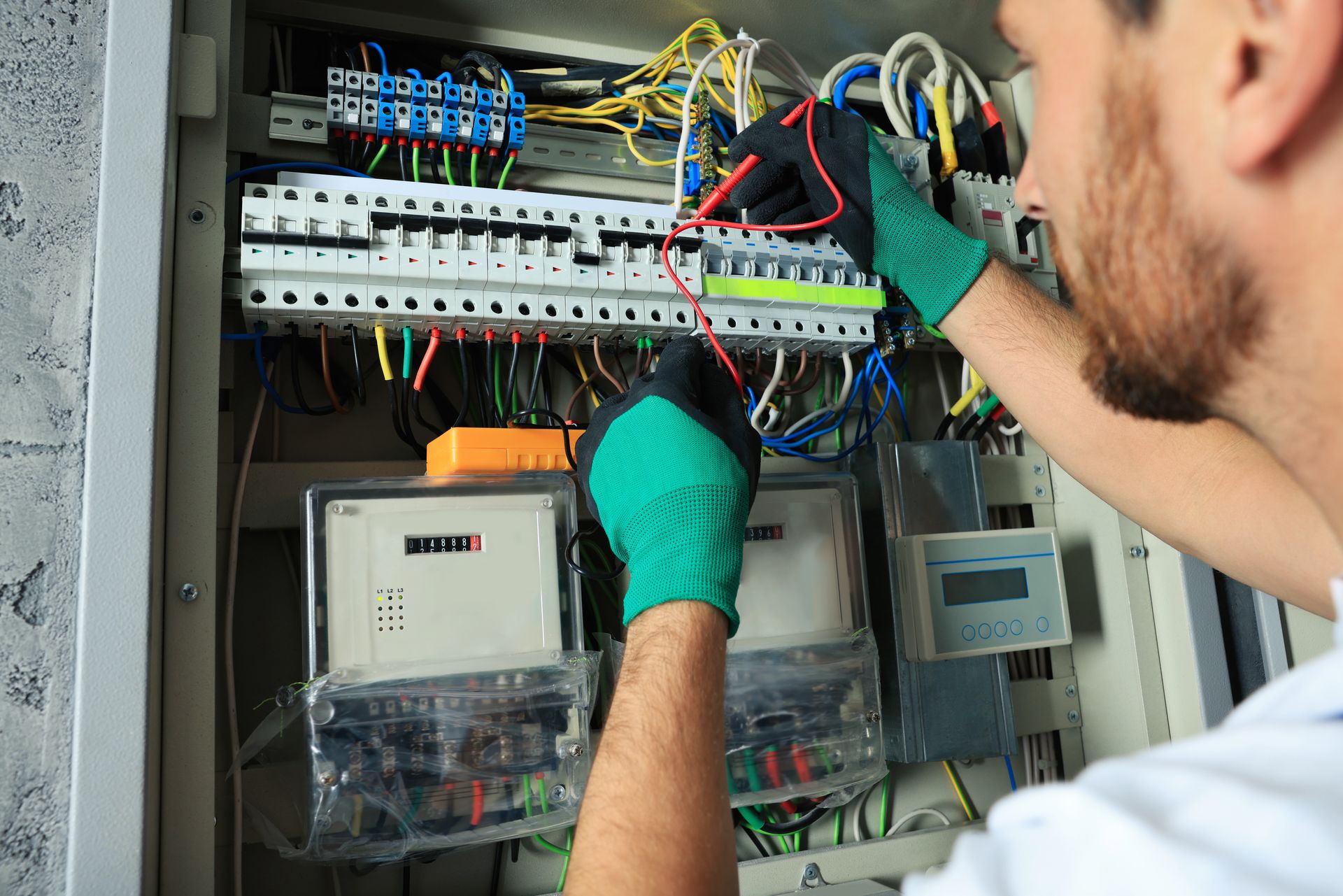 Technician wiring an electrical control panel with blue, red, and yellow cables