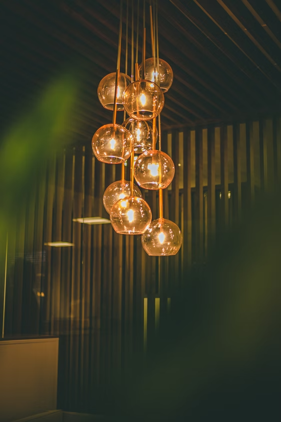 Warm amber pendant lights with glass globes hanging in a dim, modern interior