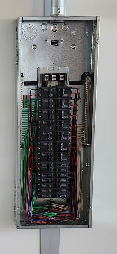 Open electrical breaker panel with wires and circuit breakers visible inside a metal box