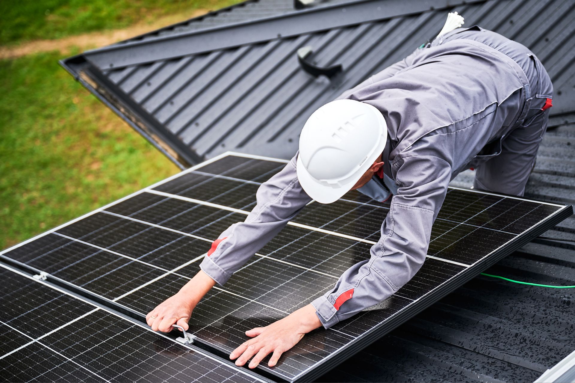 Worker in white hard hat cleaning a rooftop solar panel array