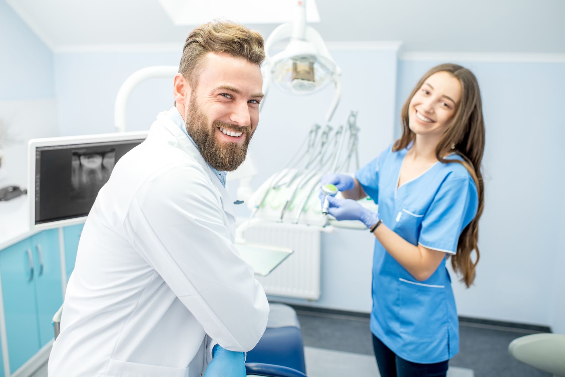 Smiling dentist and assistant in a bright, modern dental treatment room.