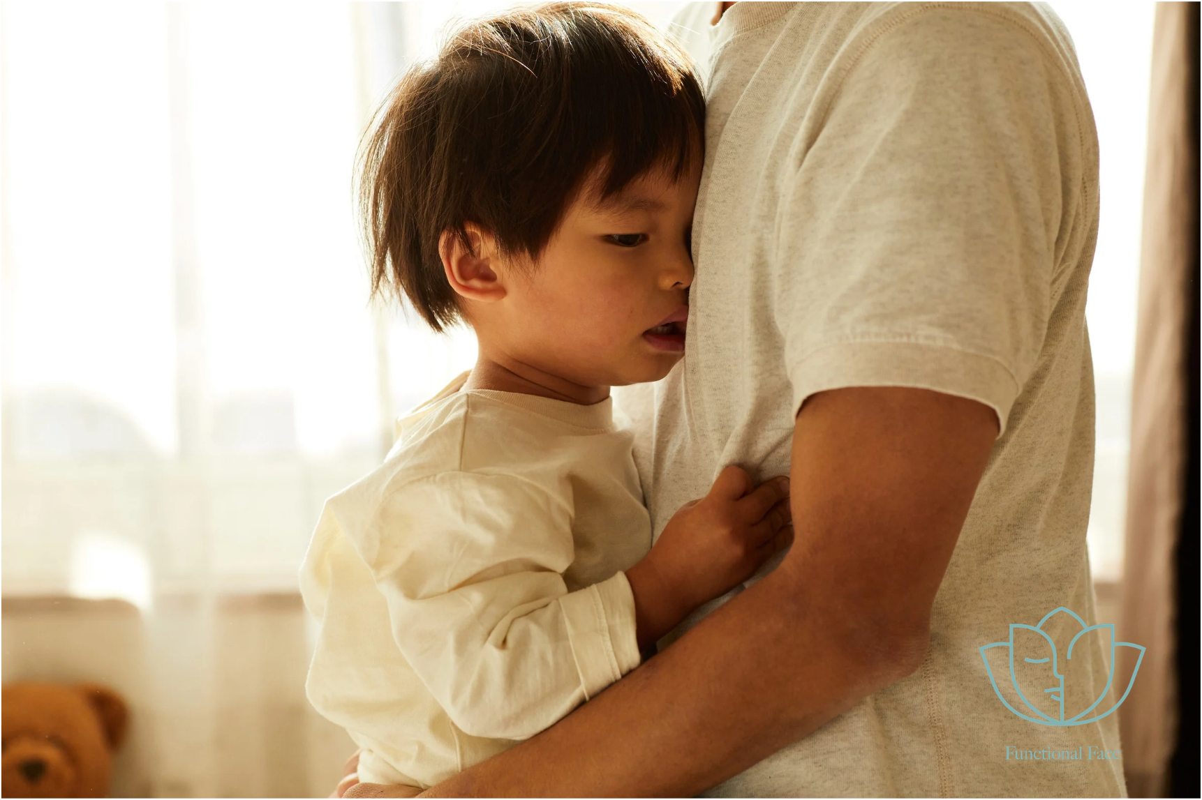 
Young child resting against a caregiver’s chest with their mouth slightly open.