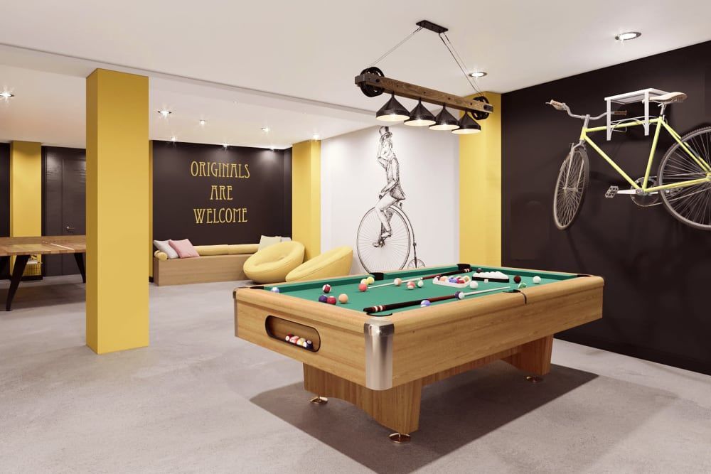 A pool table in a room with a bicycle on the wall.
