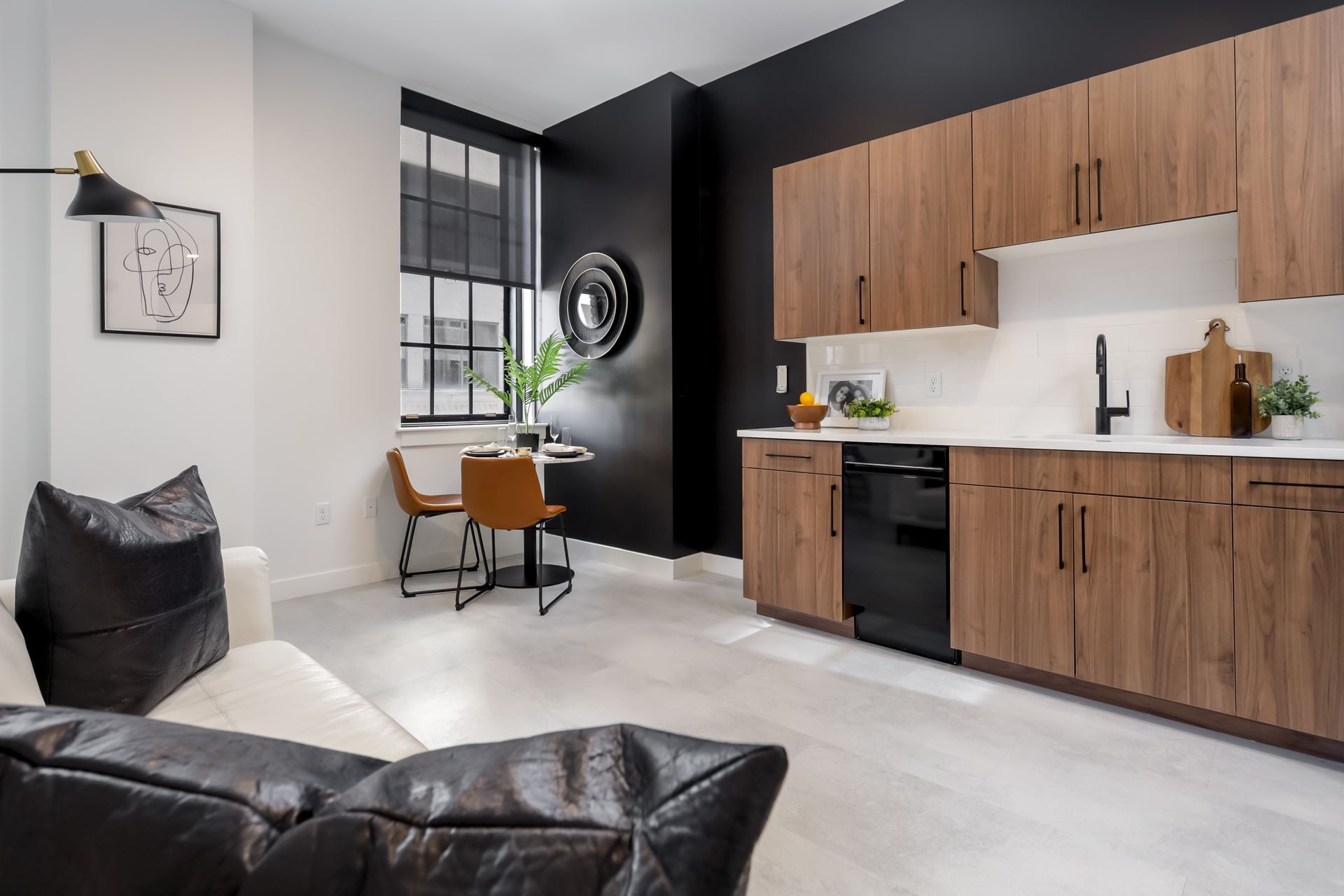 Modern kitchen and dining area with dark cabinetry, black wall, and small round table.
