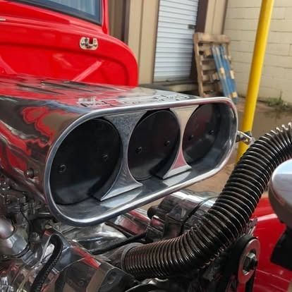 A close up of a red truck engine with a hose attached to it