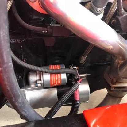 A close up of a hose and a starter on a car