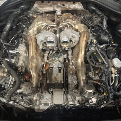 A close up of the engine of a car with the hood open.