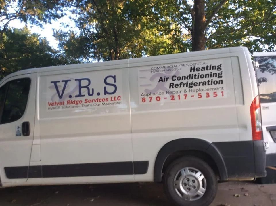 White V.R.S. HVAC service van parked outdoors with trees in the background